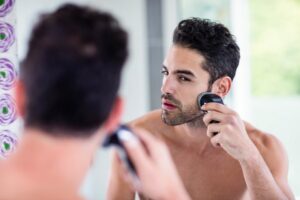 Man shaving in the mirror in the bathroom