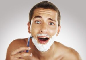 Man shaving in bathroom with manual razor